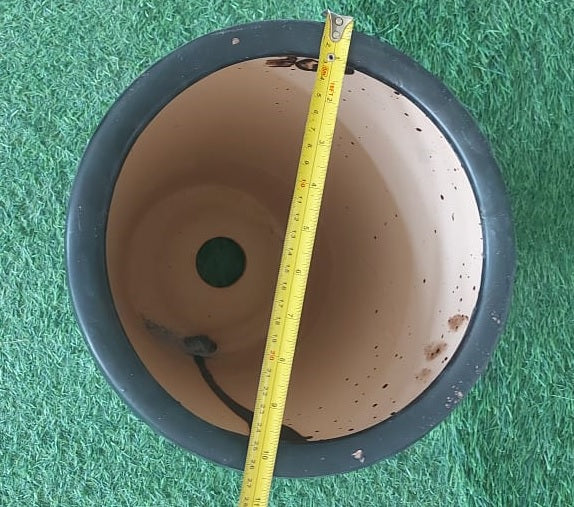 Empty plant pot with drainage hole and measuring tape on artificial grass