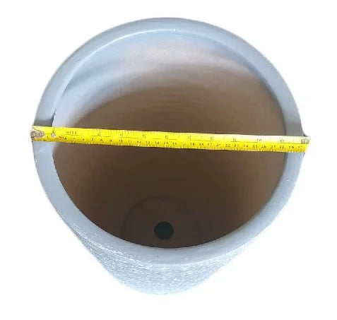 Top view of a round plant pot with a tape measure showing diameter, drainage hole visible