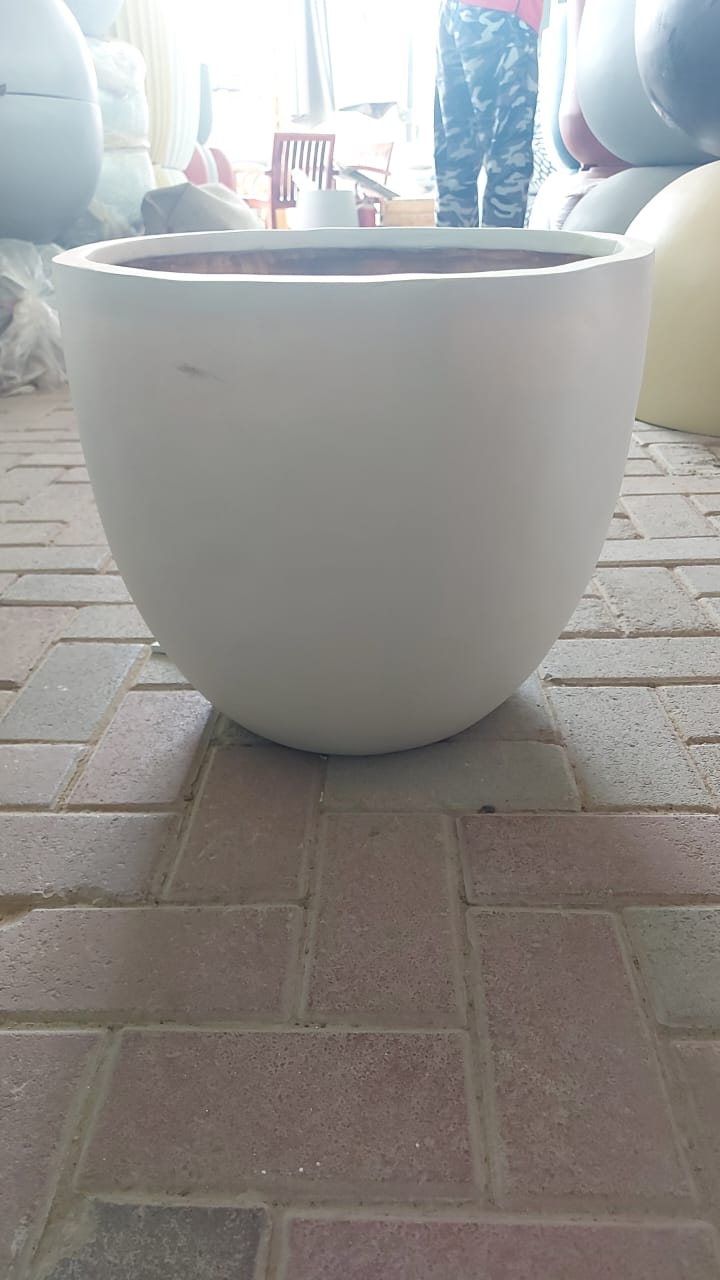 Large round white planter pot on a brick floor in a well-lit indoor setting
