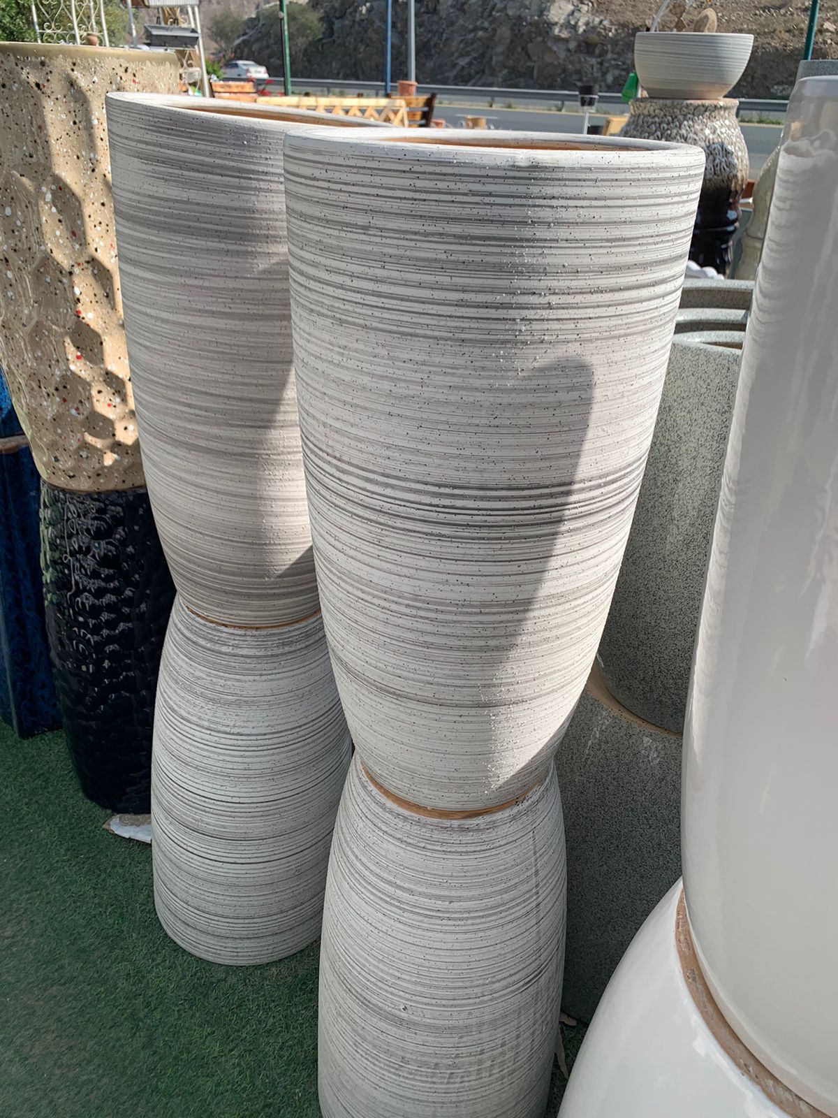 Tall striped ceramic planters displayed outdoors on artificial grass