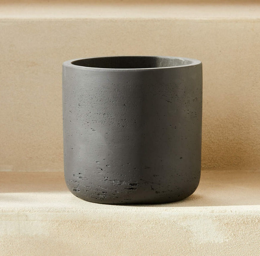 Minimalist dark gray fiber plant pot with textured surface, placed on light steps