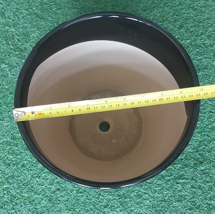 Black plant pot with drainage hole, measured across the top with tape, on artificial grass