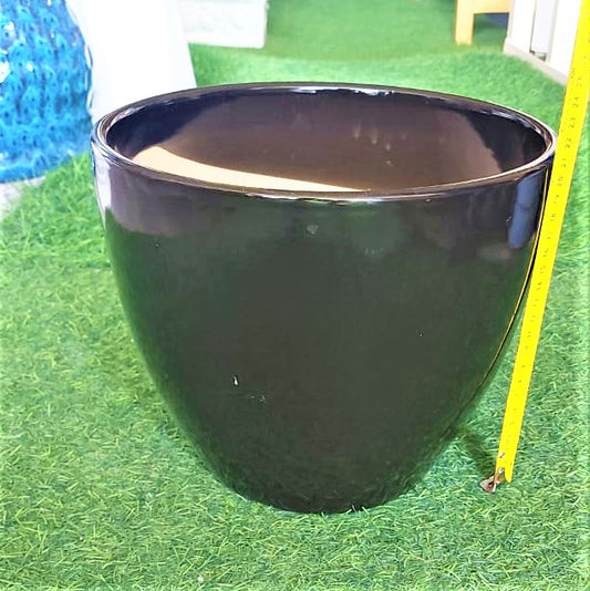 Glossy black ceramic planter pot on artificial grass with yellow measuring tape