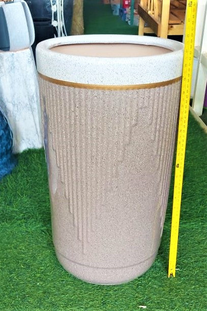 Tall cylindrical beige planter with textured vertical lines and gold accent, displayed indoors