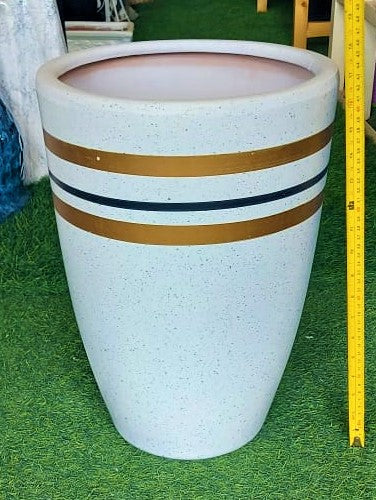 Tall white ceramic planter with gold and black stripes on artificial grass