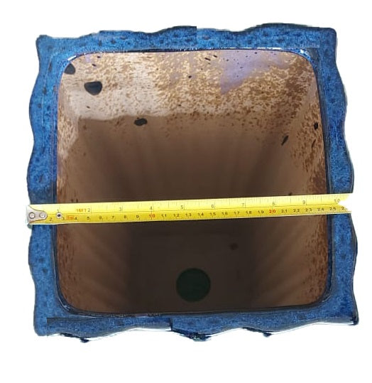 Top view of a blue square ceramic planter with measuring tape across the opening