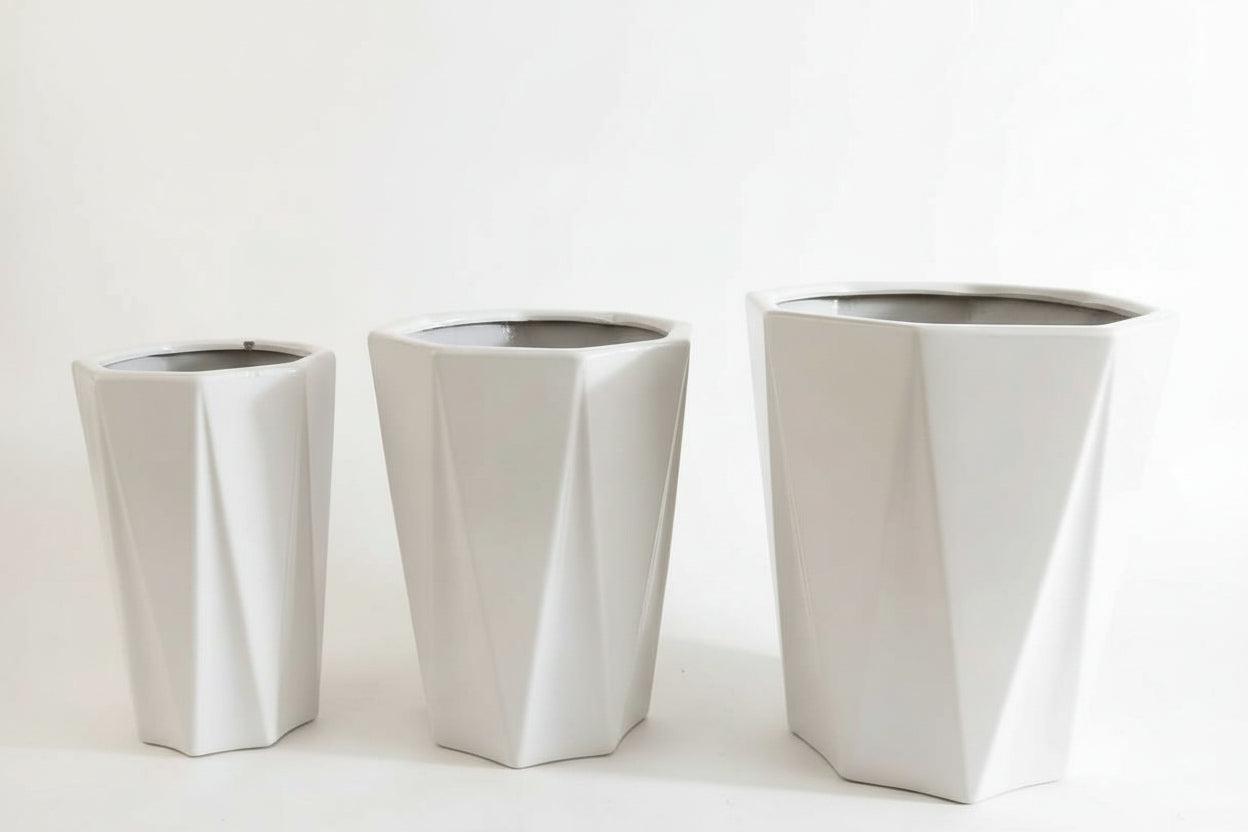 Set of three modern white geometric planters with faceted design on white background