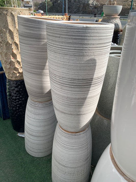 Tall striped ceramic planters displayed outdoors on artificial grass